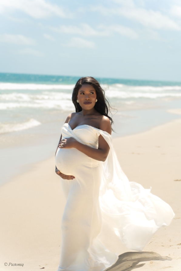 Expecting parents sitting on the grass at Cottesloe Civic Centre, sharing a joyful moment