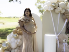 Pregnant woman standing under a large tree at Kings Park, cradling her belly