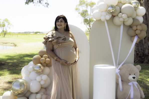 Pregnant woman standing under a large tree at Kings Park, cradling her belly